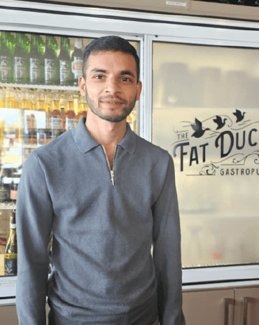 Deepak standing inside The Fat Duck Te Anau restaurant near the bar and fridge.