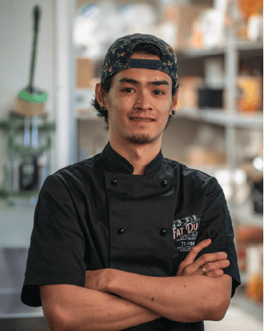 Chef Jovin standing in The Fat Duck Te Anau kitchen, wearing a chef uniform with arms crossed.