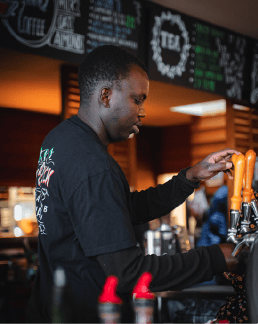 Bar staff member pouring tap beer behind the bar at The Fat Duck Te Anau restaurant.